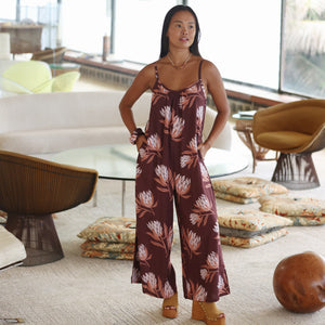 woman wearing simple brown spaghetti strap jumpsuit with protea print
