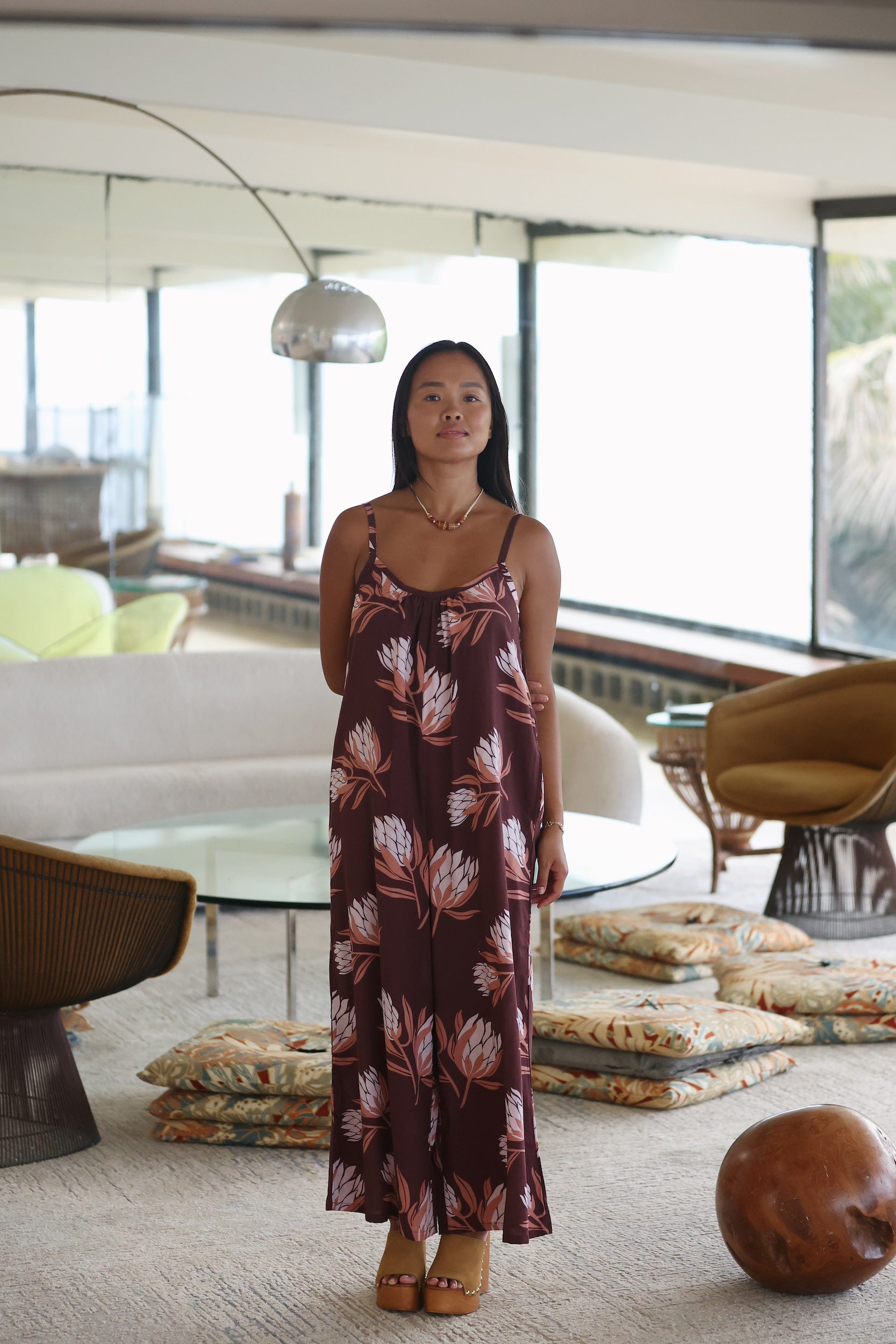 woman wearing simple brown spaghetti strap jumpsuit with protea print