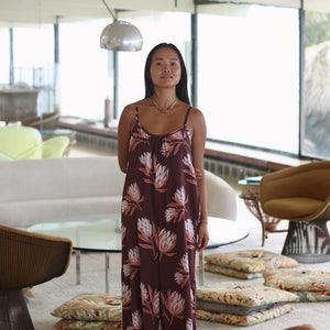 woman wearing simple brown spaghetti strap jumpsuit with protea print