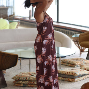 woman wearing simple brown spaghetti strap jumpsuit with protea print