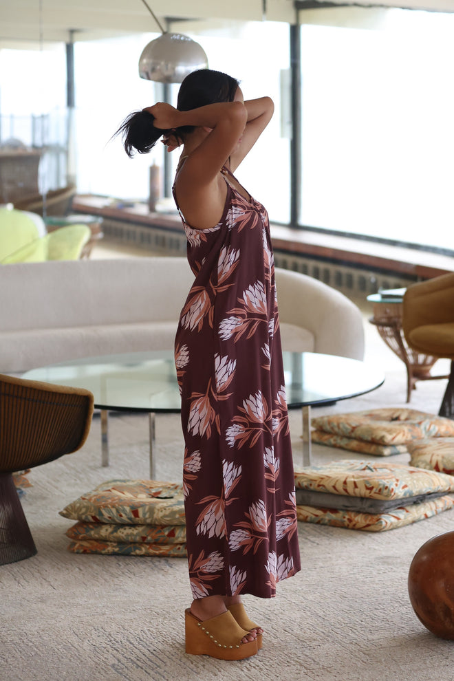 woman wearing simple brown spaghetti strap jumpsuit with protea print