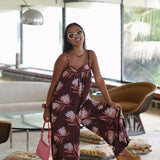 woman wearing simple brown spaghetti strap jumpsuit with protea print