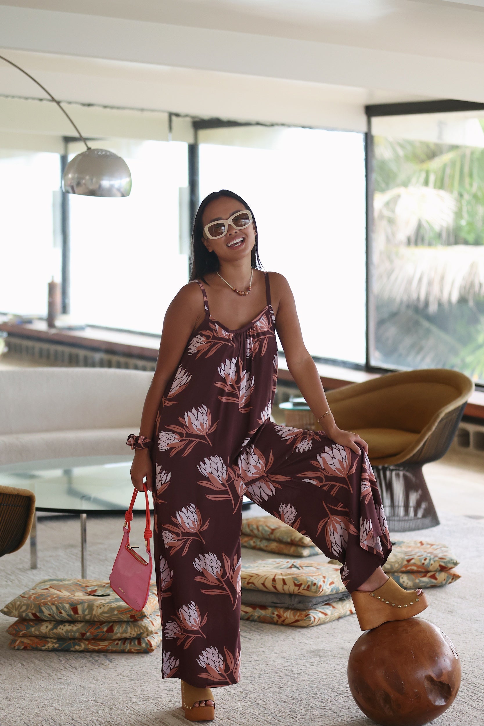 woman wearing simple brown spaghetti strap jumpsuit with protea print