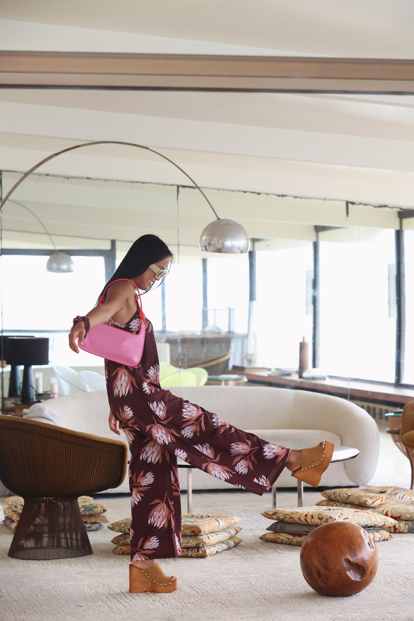 woman wearing simple brown spaghetti strap jumpsuit with protea print