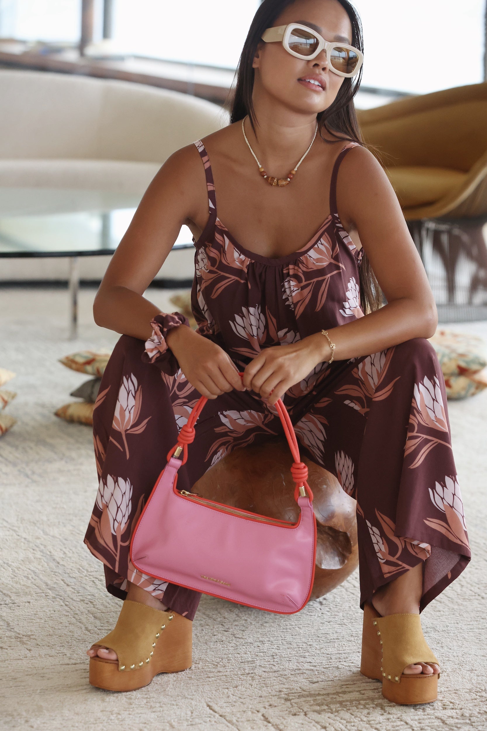 woman wearing simple brown spaghetti strap jumpsuit with protea print
