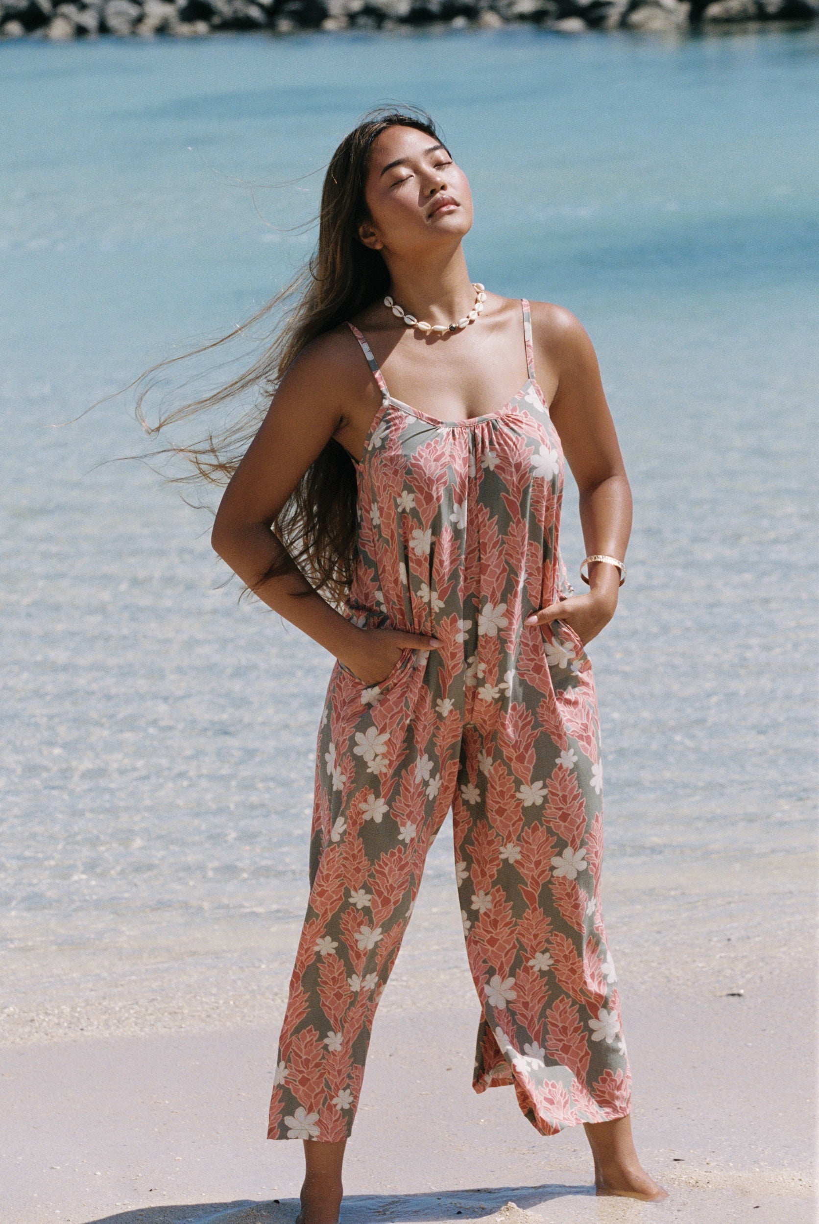 woman with brown hair wearing jade colored jumpsuit with tiare ginger print