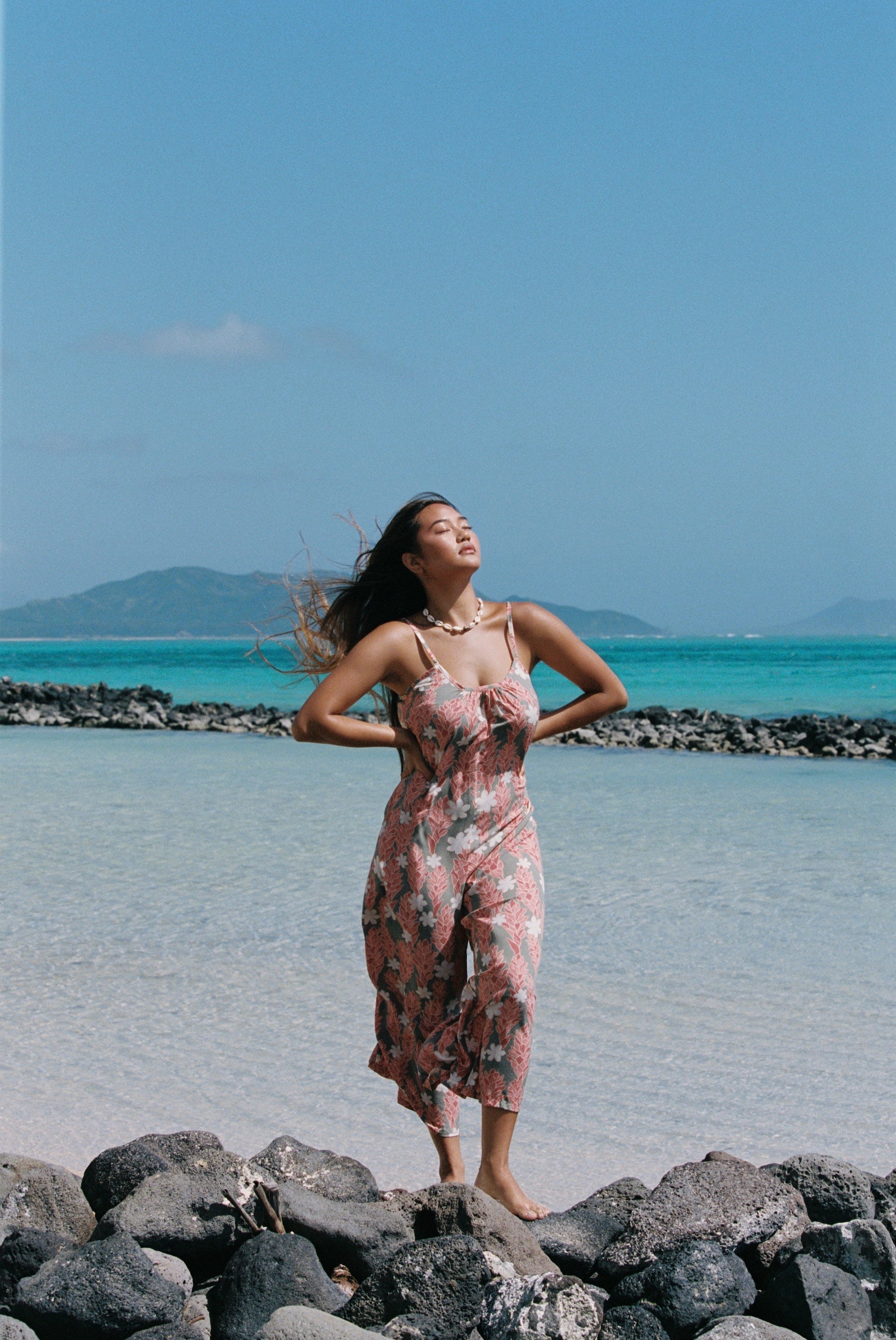 woman with brown hair wearing jade colored jumpsuit with tiare ginger print