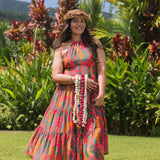 woman with brown hair wearing a colorful flowy maxi dress with tropical lei print