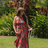 woman with brown hair wearing a colorful flowy maxi dress with tropical lei print