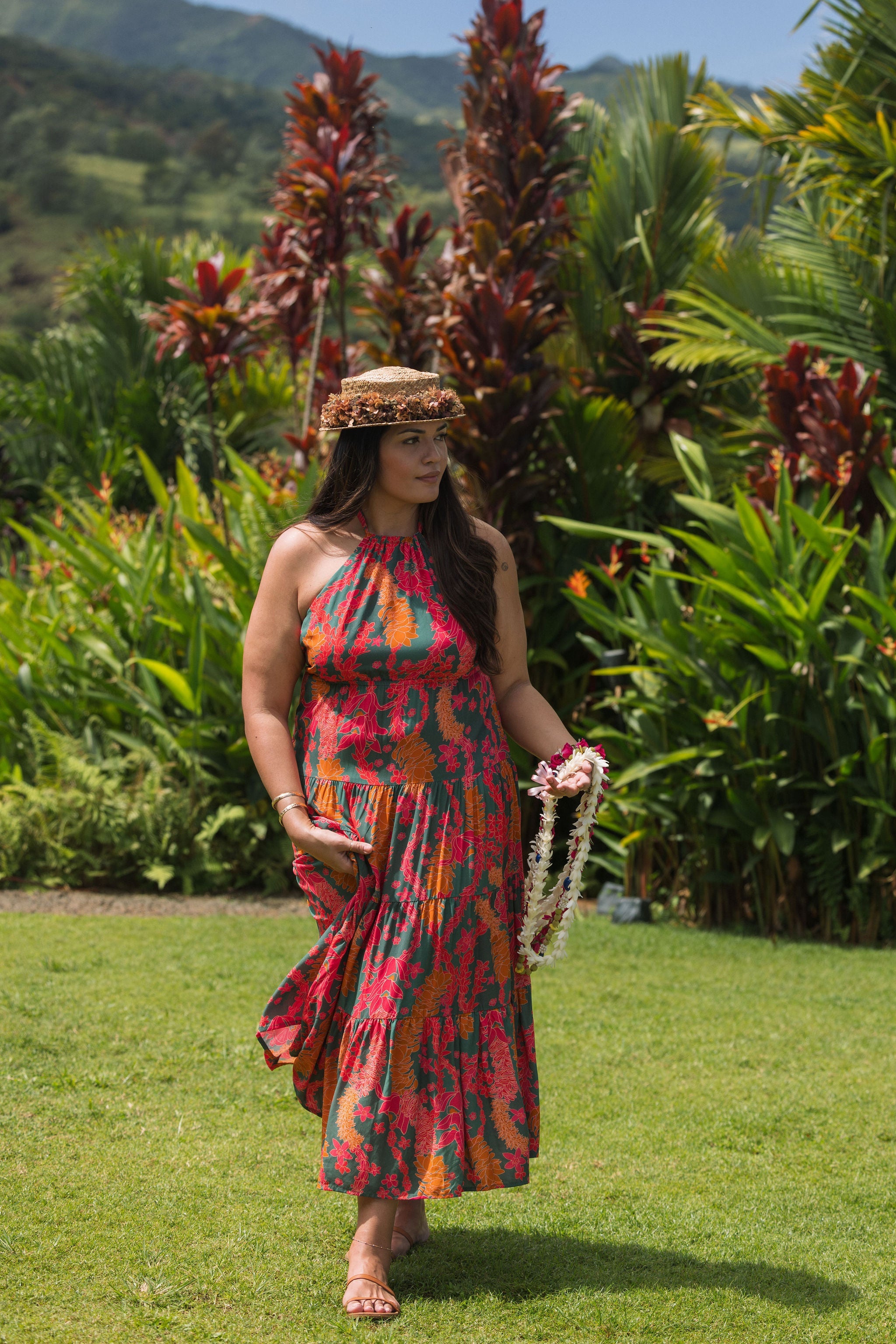 woman with brown hair wearing a colorful flowy maxi dress with tropical lei print