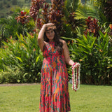 woman with brown hair wearing a colorful flowy maxi dress with tropical lei print