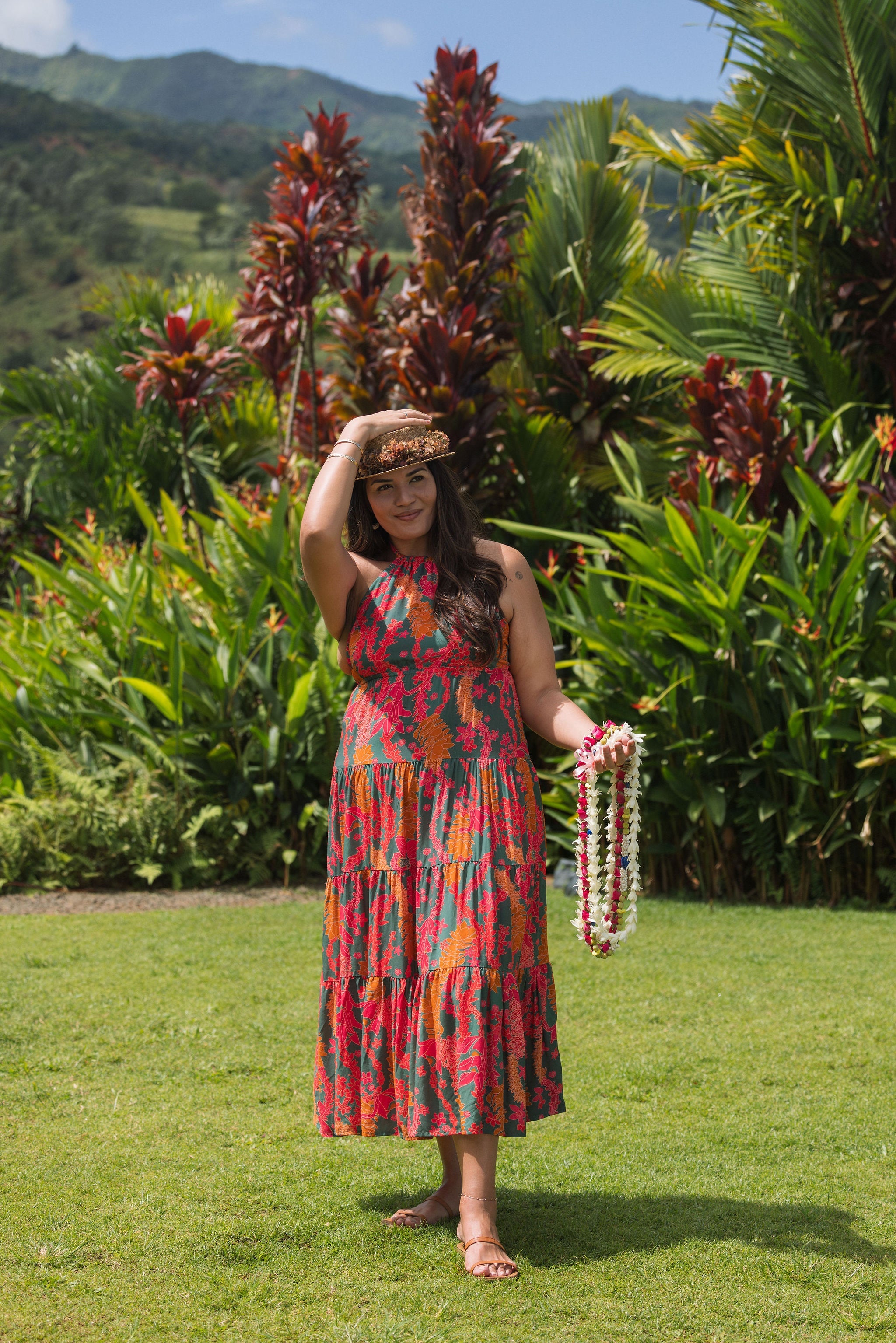 woman with brown hair wearing a colorful flowy maxi dress with tropical lei print