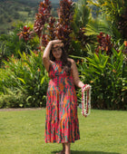woman with brown hair wearing a colorful flowy maxi dress with tropical lei print