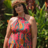 woman with brown hair wearing a colorful flowy maxi dress with tropical lei print