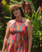 woman with brown hair wearing a colorful flowy maxi dress with tropical lei print