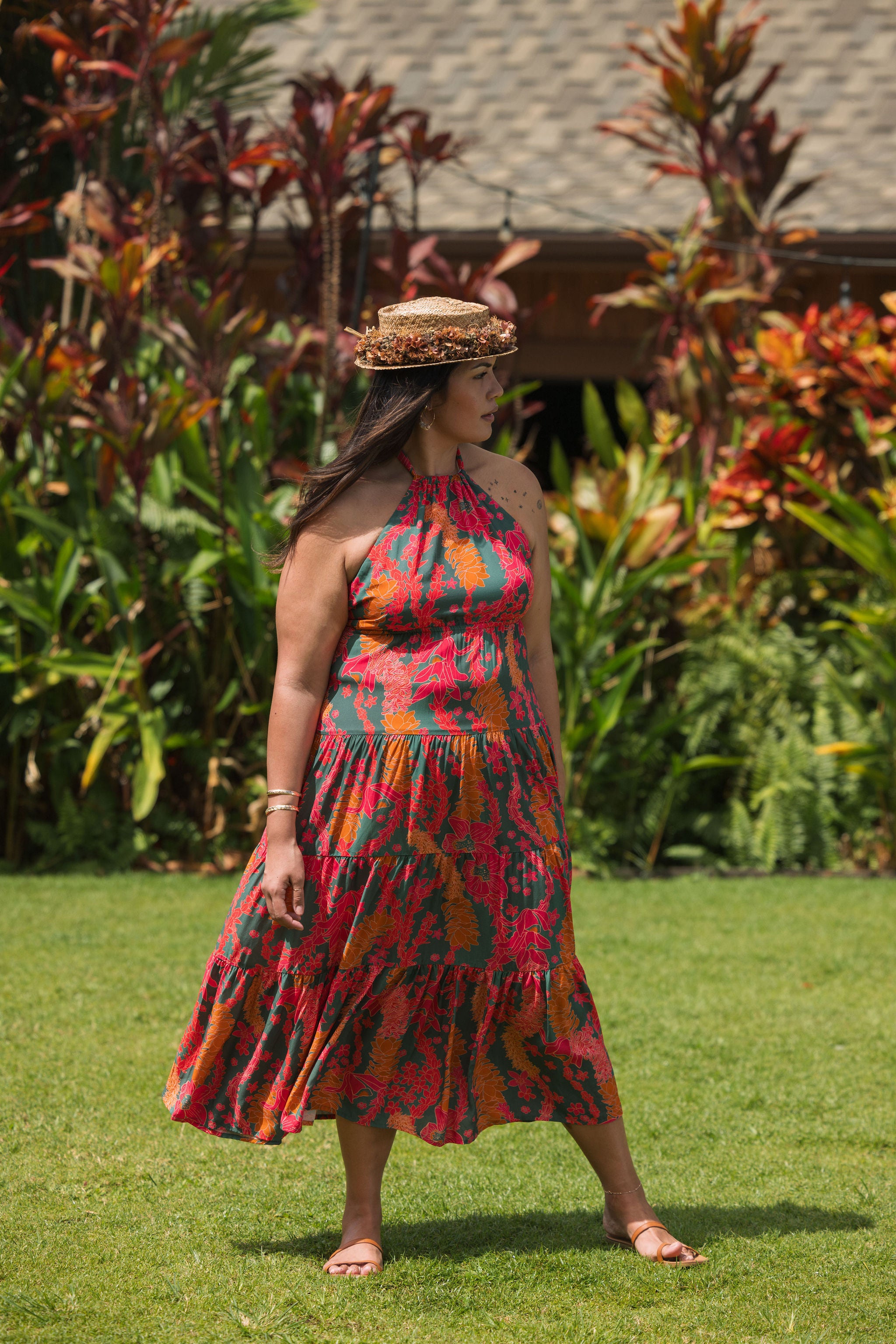woman with brown hair wearing a colorful flowy maxi dress with tropical lei print