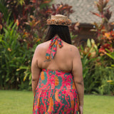 woman with brown hair wearing a colorful flowy maxi dress with tropical lei print
