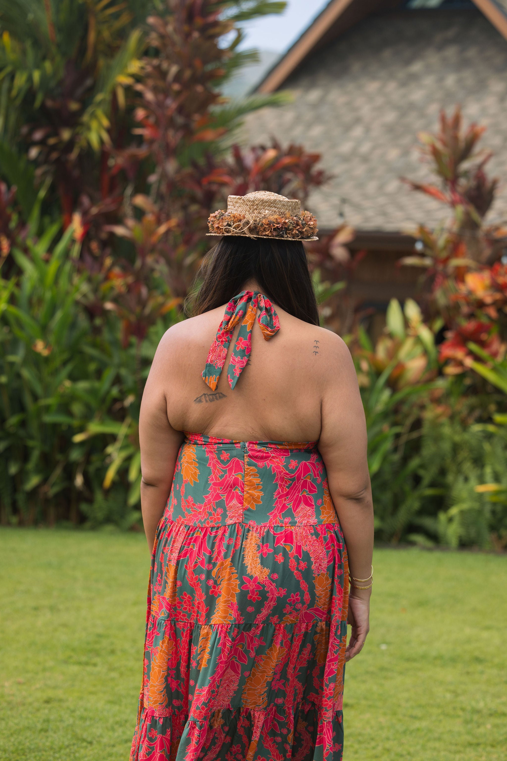 woman with brown hair wearing a colorful flowy maxi dress with tropical lei print