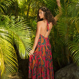 woman with brown hair wearing a colorful flowy maxi dress with tropical lei print