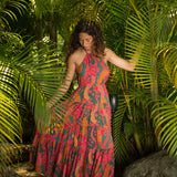 woman with brown hair wearing a colorful flowy maxi dress with tropical lei print