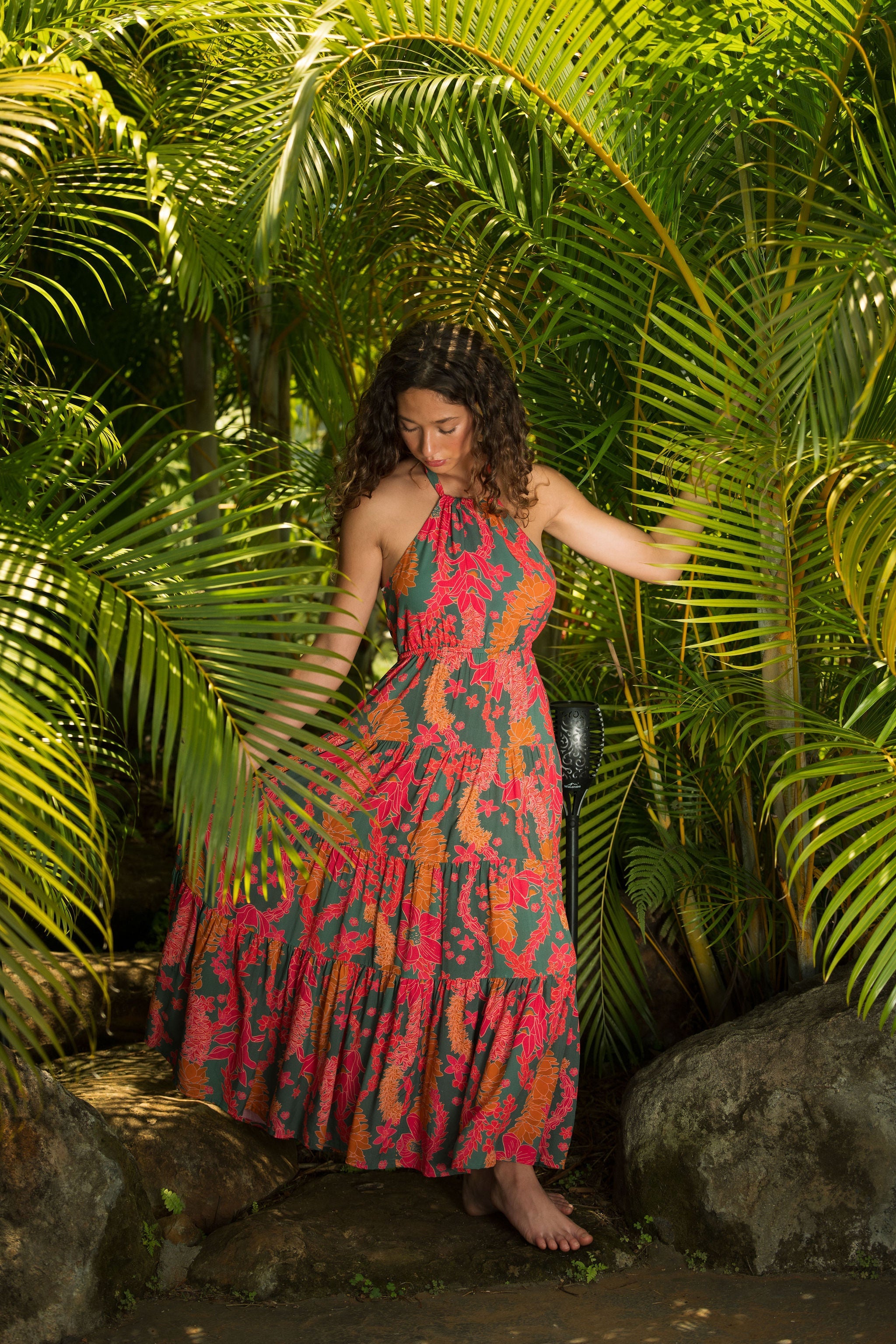woman with brown hair wearing a colorful flowy maxi dress with tropical lei print