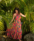 woman with brown hair wearing a colorful flowy maxi dress with tropical lei print