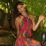 woman with brown hair wearing a colorful flowy maxi dress with tropical lei print