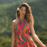woman with brown hair wearing a colorful flowy maxi dress with tropical lei print