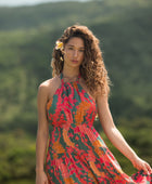 woman with brown hair wearing a colorful flowy maxi dress with tropical lei print