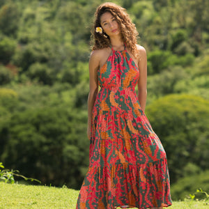 woman with brown hair wearing a colorful flowy maxi dress with tropical lei print