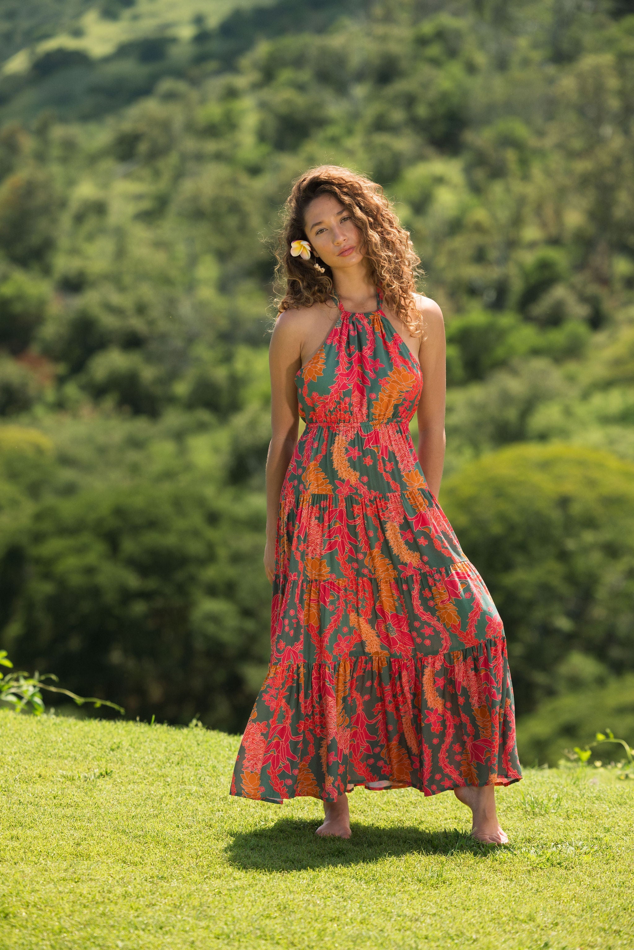 woman with brown hair wearing a colorful flowy maxi dress with tropical lei print