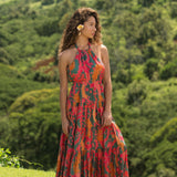 woman with brown hair wearing a colorful flowy maxi dress with tropical lei print