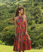 woman with brown hair wearing a colorful flowy maxi dress with tropical lei print