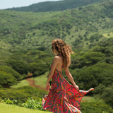 woman with brown hair wearing a colorful flowy maxi dress with tropical lei print