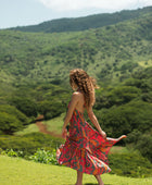 woman with brown hair wearing a colorful flowy maxi dress with tropical lei print