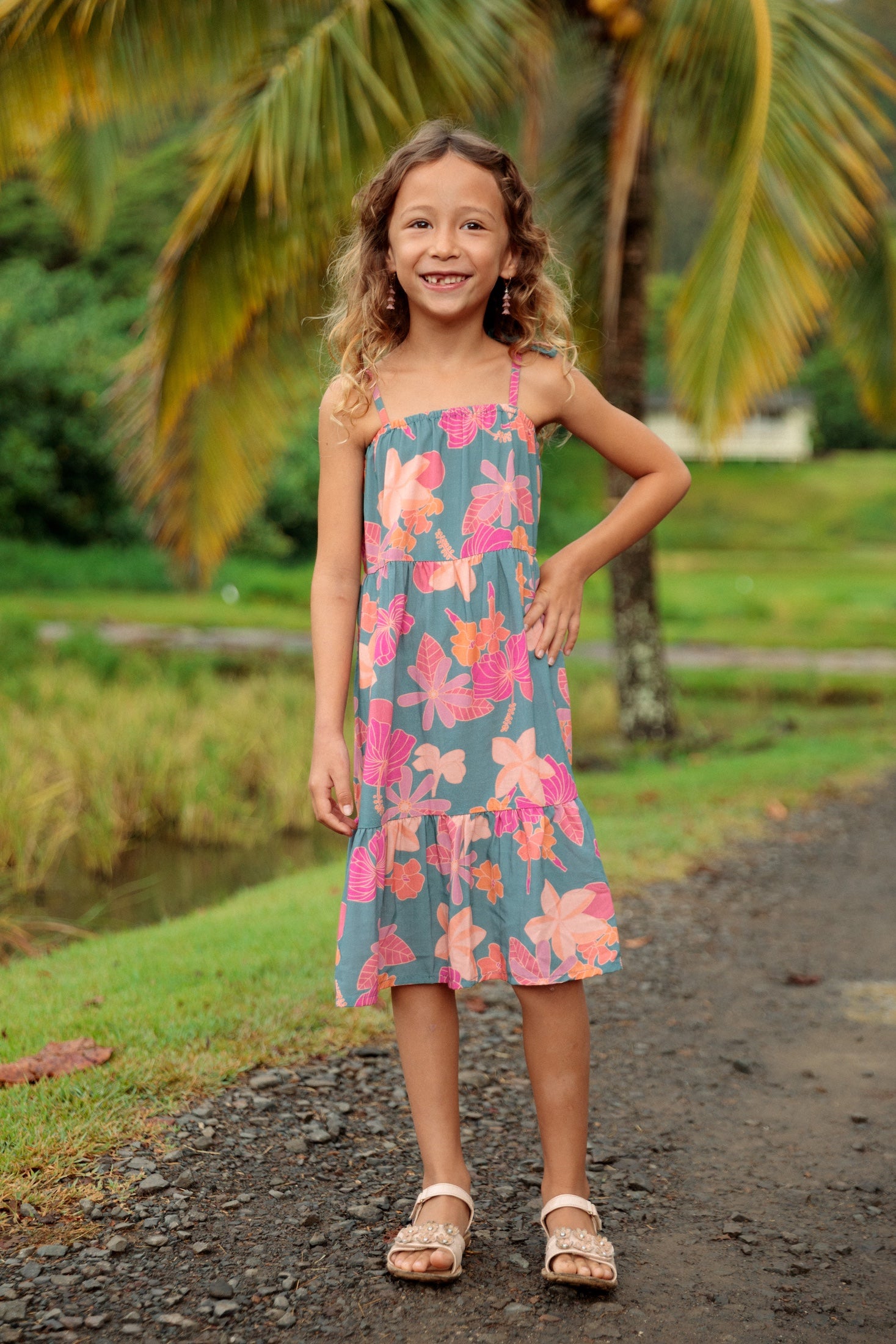 little girl wearing long teal dress with tie sleeve and floral pattern