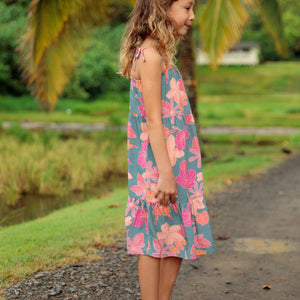 little girl wearing long teal dress with tie sleeve and floral pattern