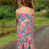 little girl wearing long teal dress with tie sleeve and floral pattern