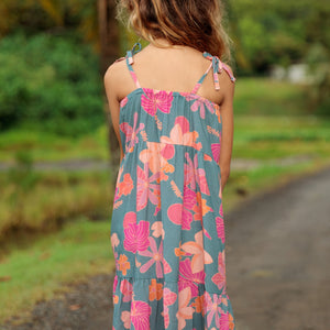 little girl wearing long teal dress with tie sleeve and floral pattern