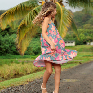 little girl wearing long teal dress with tie sleeve and floral pattern