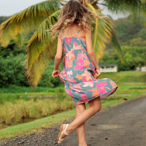 little girl wearing long teal dress with tie sleeve and floral pattern