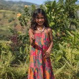 girl with brown hair wearing a colorful dress with tropical lei print