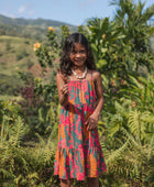 girl with brown hair wearing a colorful dress with tropical lei print
