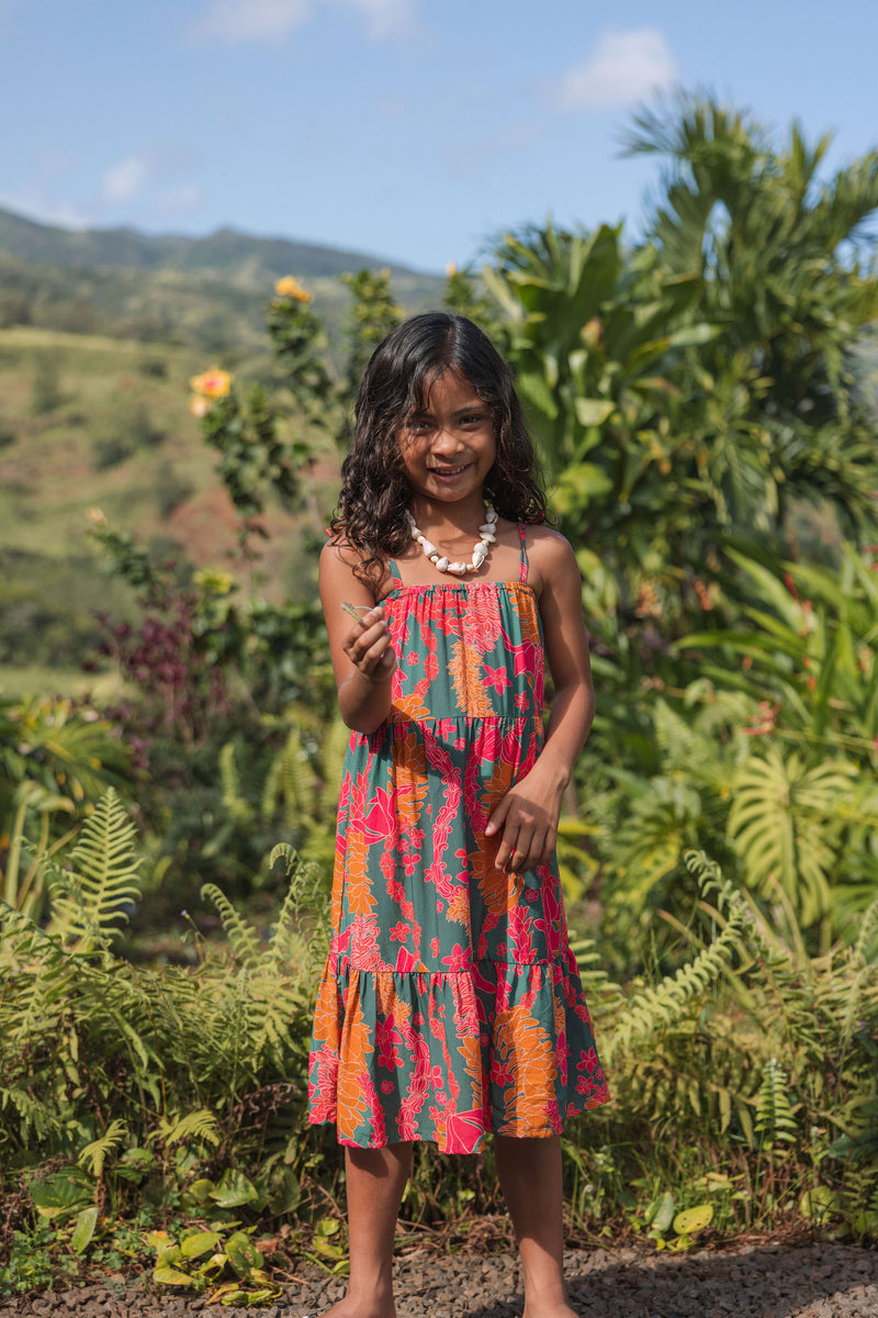 girl with brown hair wearing a colorful dress with tropical lei print