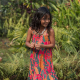girl with brown hair wearing a colorful dress with tropical lei print