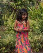 girl with brown hair wearing a colorful dress with tropical lei print