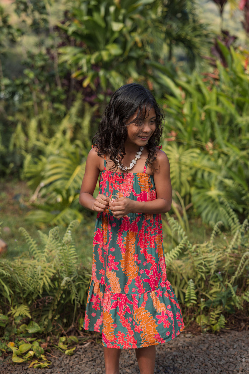 girl with brown hair wearing a colorful dress with tropical lei print