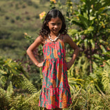 girl with brown hair wearing a colorful dress with tropical lei print