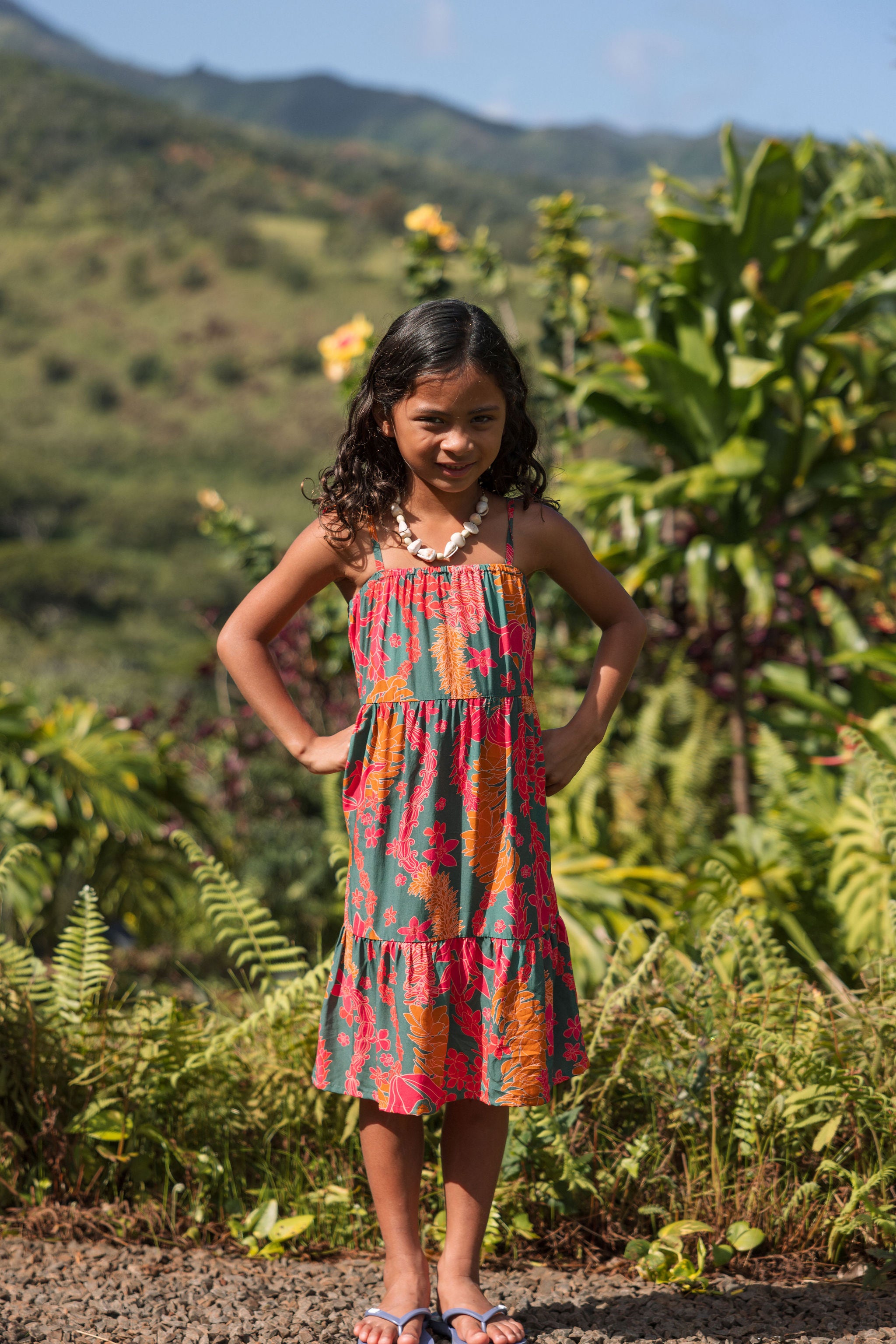 girl with brown hair wearing a colorful dress with tropical lei print
