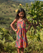 girl with brown hair wearing a colorful dress with tropical lei print